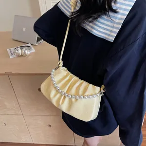 Detailed view of pale yellow pleated bag with pearl chain handle and smooth PU texture