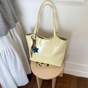 Detail view of cream leather tote bag with star charm on wooden stool with soft lighting