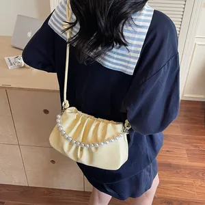 Detailed close-up of cream pleated shoulder bag featuring elegant pearl chain and soft texture
