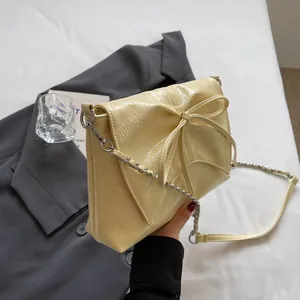Detail der hellgelben Vintage-Faltenledertasche mit großer Schleife und Silberkette