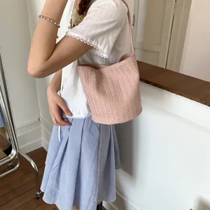 Pink woven bucket bag in vintage style worn as a stylish shoulder bag for women