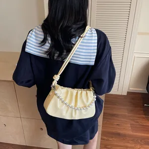 Close-up of ruched detail and elegant pearl strap on the yellow shoulder bag