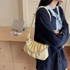 Detailed view of the pleated cream shoulder bag with pearl chain and glossy finish