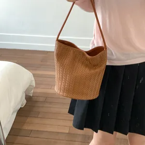 Detailed close-up of the woven leather texture on a large caramel bucket tote bag