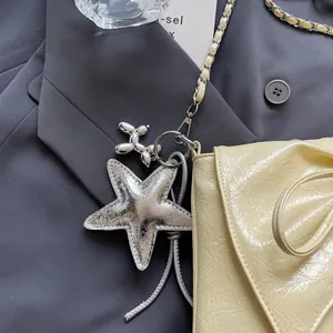 Detail der gerafften creme Ledertasche mit silbernem Seestern und Hund Anhänger