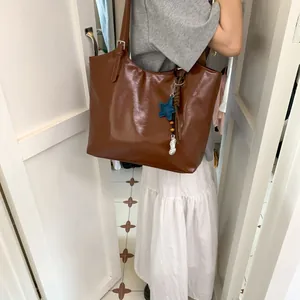 Detail of a brown leather tote bag showing the adjustable strap and star pendant