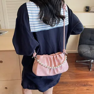 Detail of pink pleated shoulder bag with decorative pearls on a navy blue top