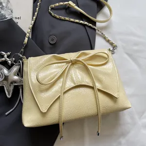 Detail der hellgelben Tasche mit Faltenleder, großer Schleife und silberner Kette
