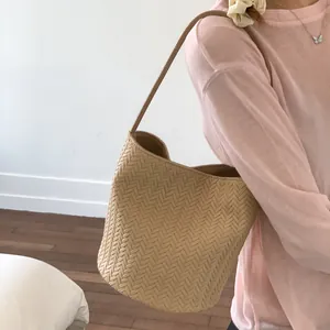Close-up of beige woven leather texture and large capacity bucket tote shoulder bag