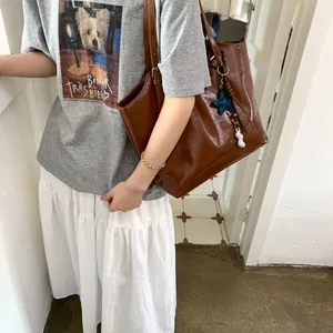 Detail of dark brown tote bag featuring unique blue star and silver peanut charms