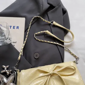 Detail der cremefarbenen Lackledertasche mit Schleife, Silberkette und Hundeanhänger
