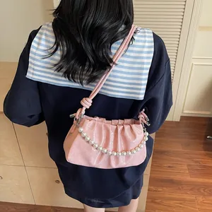 Detailed view of pink pleated underarm bag featuring glossy finish and pearl chain accents