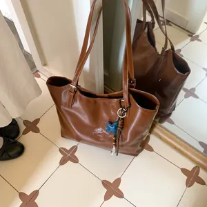 Detail of a brown glossy tote bag with a star charm on vintage tiled flooring