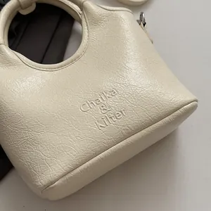 Dettaglio borsa crema con trama in pelle stropicciata e logo Chaika & Kilter