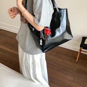 Detail of glossy black tote bag with red star pendant and peanut charm accessory