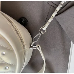 Close-up of quilted beige leather texture with rhinestones and silver chain strap details