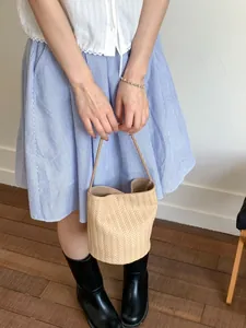 Chic beige woven bucket bag with elegant V-texture and slim shoulder straps
