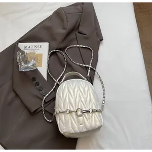 Close-up of a white quilted mini backpack with silver metal and leather chain straps