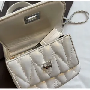 Macro shot of white quilted mini chain bag interior showing lipstick storage and silver lock