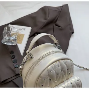 Detail of a quilted rhinestone backpack in beige leather on a brown blazer backdrop