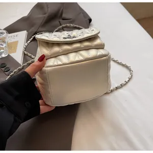 Detailed view of beige quilted mini backpack with silver rivets and metal chain strap