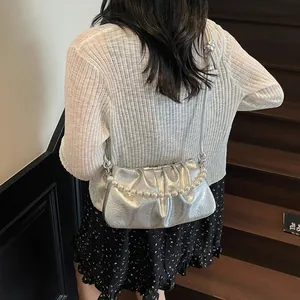 Detailed view of silver pleated shoulder bag with elegant large pearl handle strap