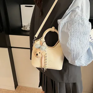Dettaglio della borsa in pelle crema con goffratura haika & fter e ciondolo a orsetto