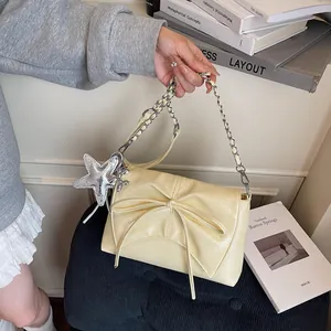 Detailansicht der cremefarbenen Tasche mit Schleife, Silberkette und Sternanhänger