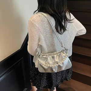 Close-up of pleated silver metallic bag with large pearl chain and knot strap detail