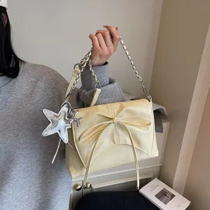 Details einer hellgelben Schleifen-Handtasche mit Silberkette und Sternanhänger