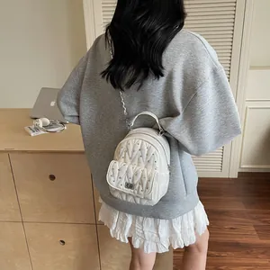 Detail of white quilted mini backpack featuring shiny rhinestones and silver chain straps