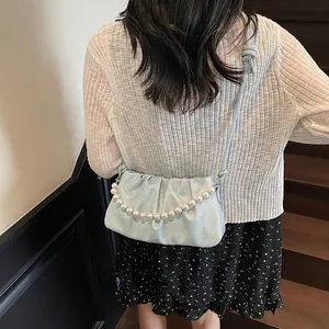 Detail of light blue ruched crossbody bag with decorative large white pearl chain