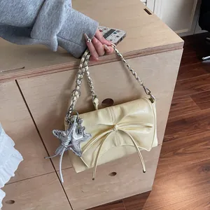 Detail der beigen Schleifentasche mit silbernem Seesternanhänger und Kette