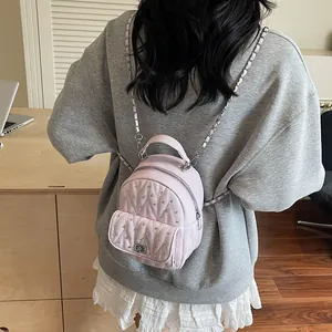 Close-up of pink quilted mini backpack with rhinestones and metal chain straps