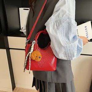 Borsa a secchiello in pelle lucida rossa con ciondolo a cane e sciarpa su modella