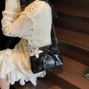 Schicke schwarze Lackledertasche mit Schleife und Sternanhänger an einem modischen Model