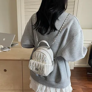 Detail of white quilted mini backpack featuring rhinestones and metal chain straps