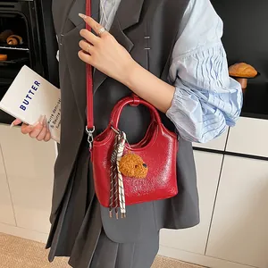 Dettaglio borsa tote in pelle verniciata rossa con ciondolo a orsetto e foulard