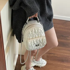 Close-up of quilted white mini backpack with sparkling rhinestones and silver chain strap