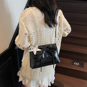 Detail einer schwarzen glänzenden Handtasche mit Schleife und Sternanhänger auf Treppen