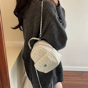 Detailed back view of a mini cream quilted backpack with silver studs and chain straps