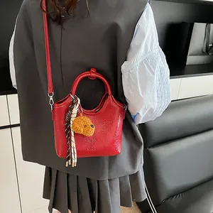 Dettaglio della borsa in pelle lucida rossa con logo goffrato e ciondolo a cucciolo
