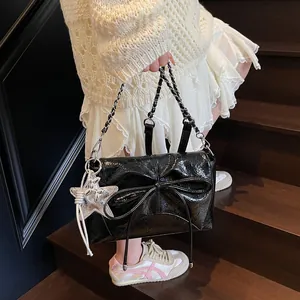 Detail der glänzenden schwarzen Handtasche mit großer Schleife und silbernem Sternanhänger