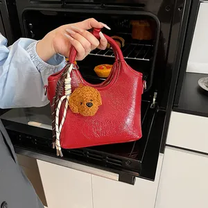 Dettaglio della borsa rossa in pelle stropicciata con ciondolo teddy e nappe