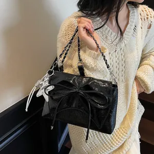 Detail der schwarzen Lacktasche mit Schleife, Kettenriemen und Stern-Anhänger