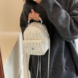 Macro view of white quilted mini backpack with rhinestone detailing and metal chain straps
