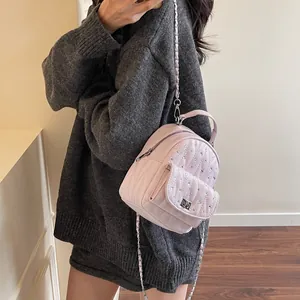 Detail of mini pink quilted backpack with rhinestones and metal chain strap on model