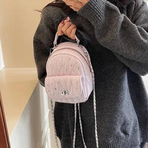 Detail of pink quilted mini backpack with rhinestones and silver chain strap on model