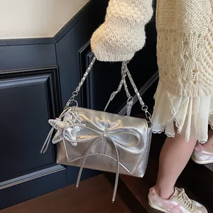 Detail der silbernen Metallic-Tasche mit großer Schleife, Seestern-Anhänger und Kette
