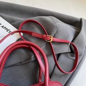 Détail du sac à main en cuir rouge avec boucle dorée et bandoulière réglable